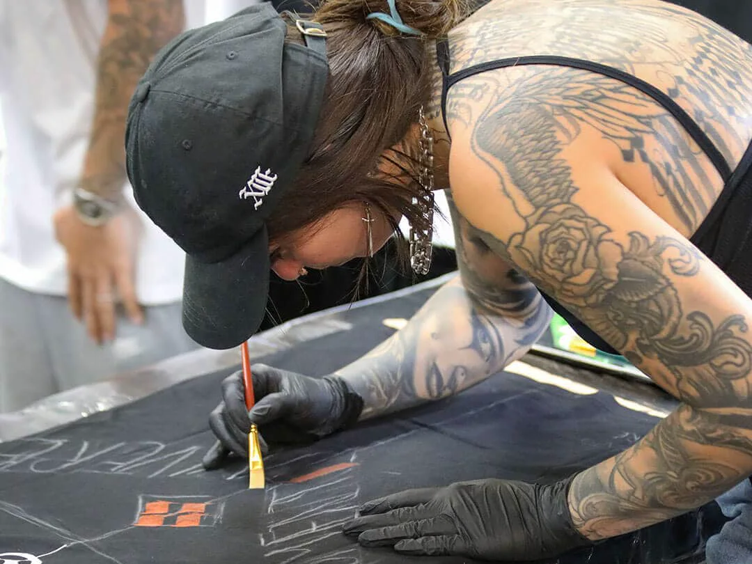 An artist hand-painting merch on the convention floor