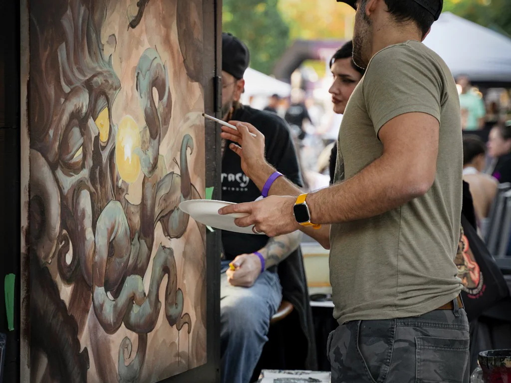 An artist painting a canvas live on the convention grounds